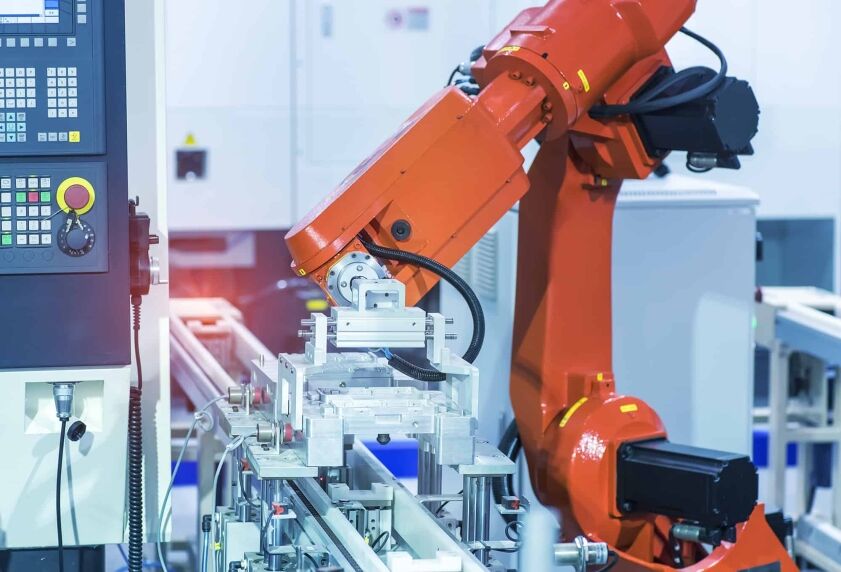 Robotic Arm picking up and moving a metal part from a conveyor belt