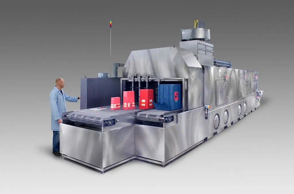 Conveyor parts washer designed to clean medical waste bins and totes.