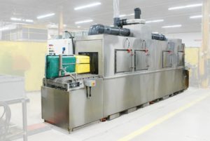 Conveyor belt washer for cleaning totes and trays used in food processing
