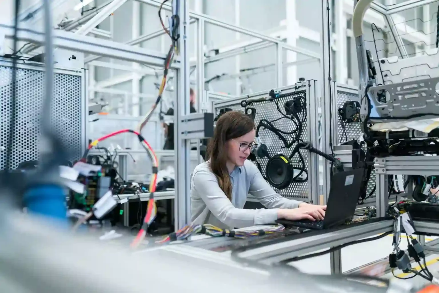 female mechanical engineer working at laptop on production line
