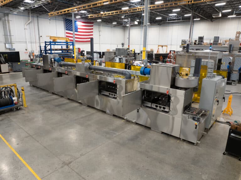 Conveyor part washer to clean wheel hubs.