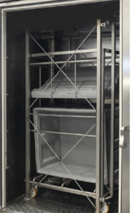 Totes and lids inside of sanitizing rack washer.