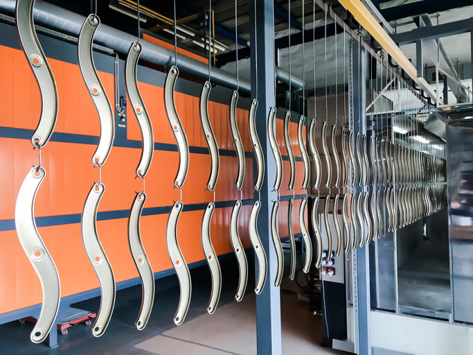 Powder coating of metal parts in factory.