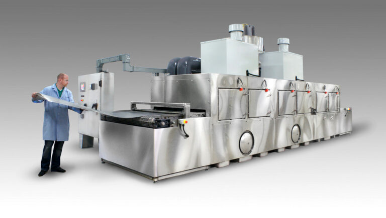 Conveyor washer designed to clean perforated stainless steel sheets.