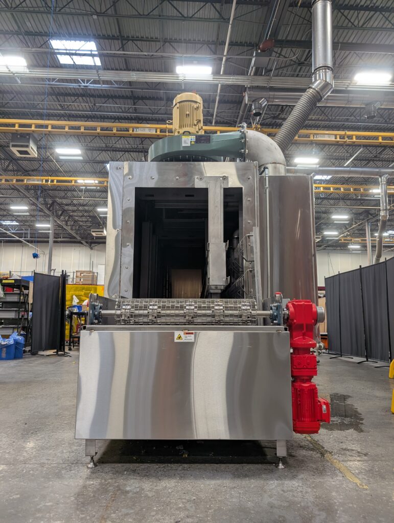 Conveyor parts washer designed to clean medical waste bins and lids.