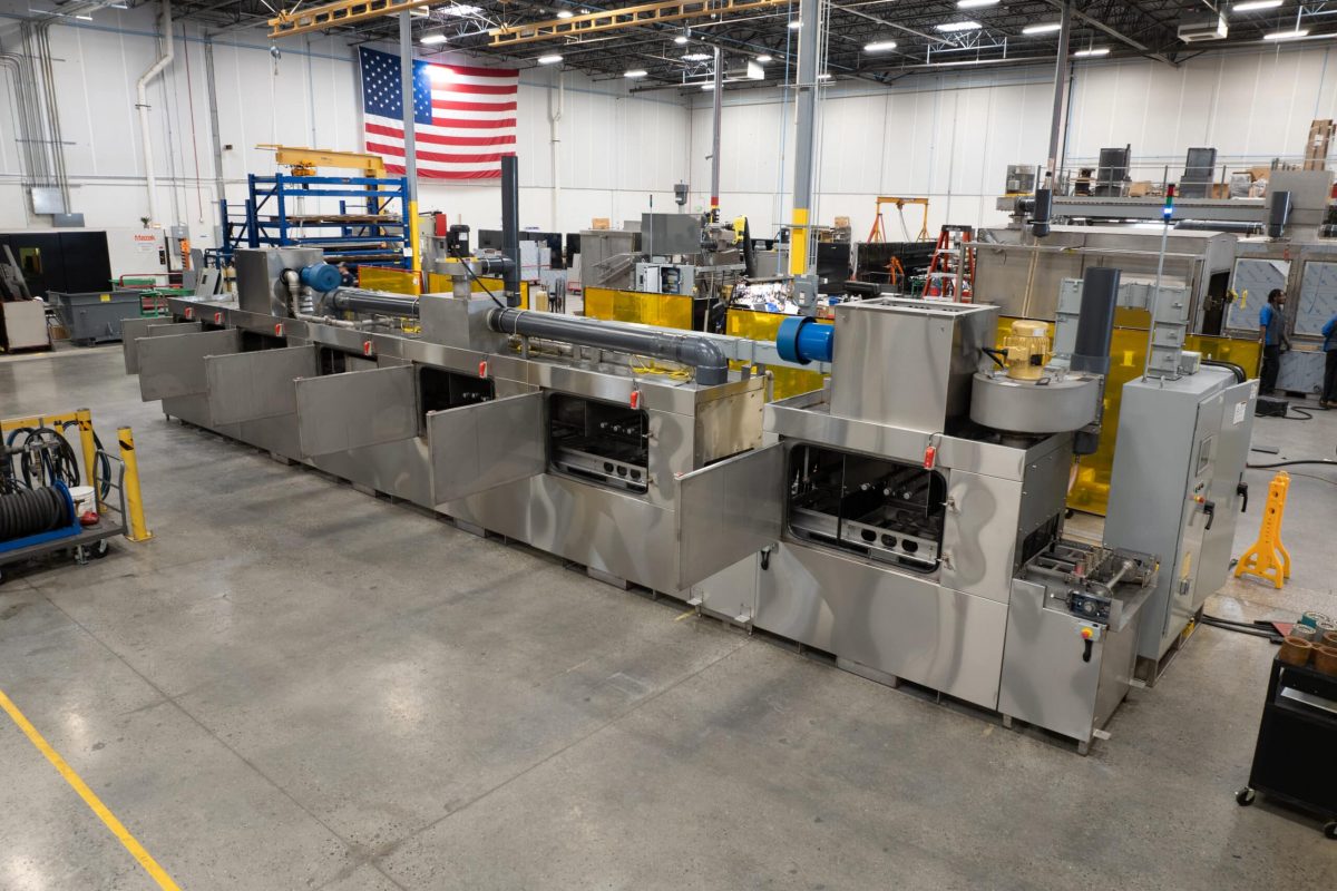 Conveyor part washer to clean wheel hubs.